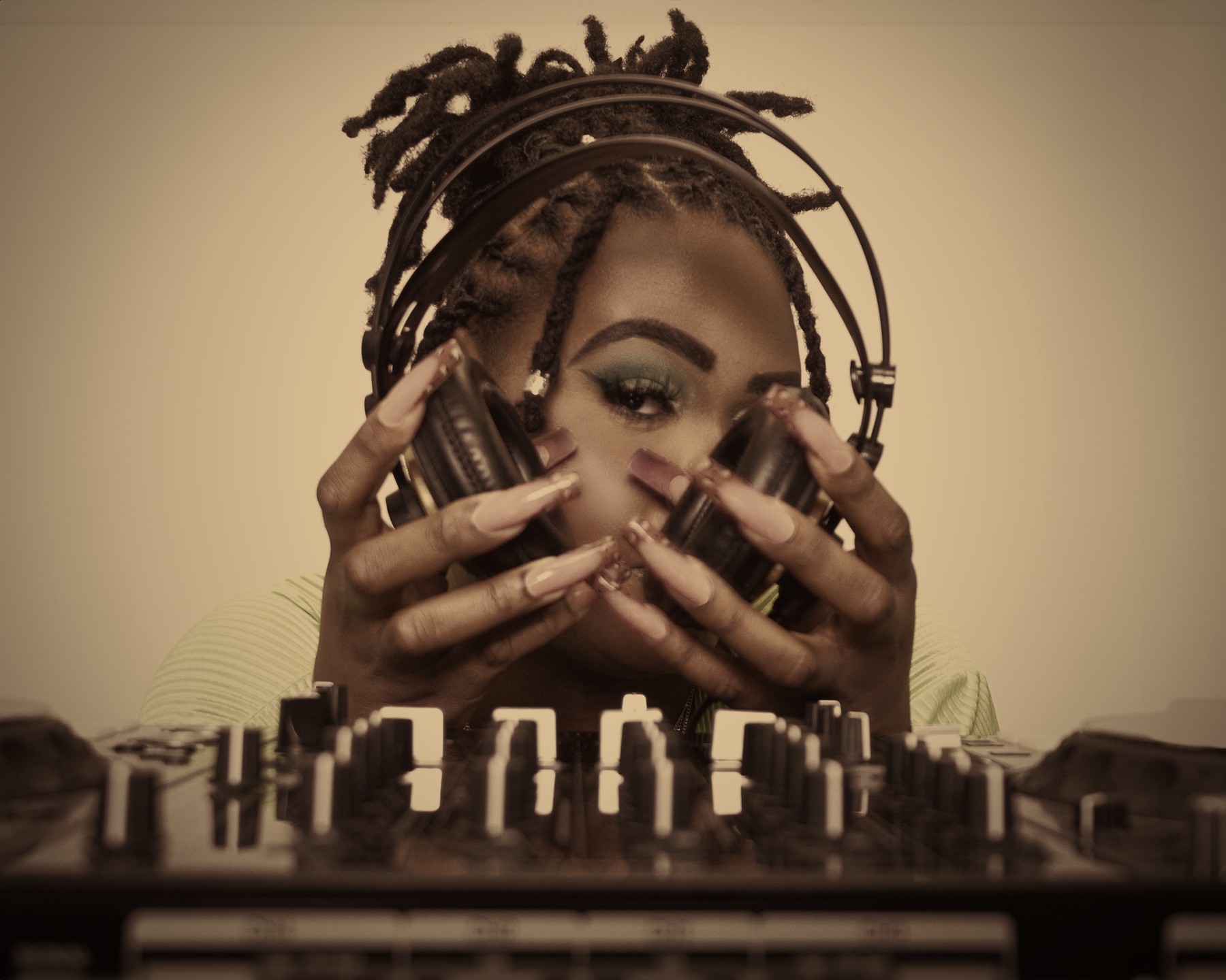 DJ Sam I Am behind the decks holding her headphones to her face
